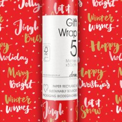 Roll of red wrapping paper decorated with white and gold lettering. The text reads 'Jolly', 'Merry', 'Bright', 'Winter Wishes', 'Happy Holidays', 'Happy Christmas', 'Jingle Bells'. 5 metres of gift wrap, sustainably sourced and recyclable.