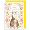 Easter card with two bunnies surrounded by pink and peach roses and daisies. Text reads Happy Easter. Card with a yellow envelope.