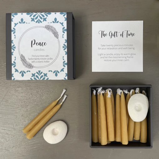 Mini candle gift set containing small beeswax candles and a small white ceramic holder. Comes in a presentation box with text 'Peace candles. Find your inner calm. Twelve twenty minute candles with a ceramic holder'.