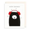 Birthday card with an illustration of a black bear wearing red headphones. Text at the top reads Happy birthday.