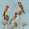 Three goldfinches perched on top of thistles against a pale blue snowy sky.