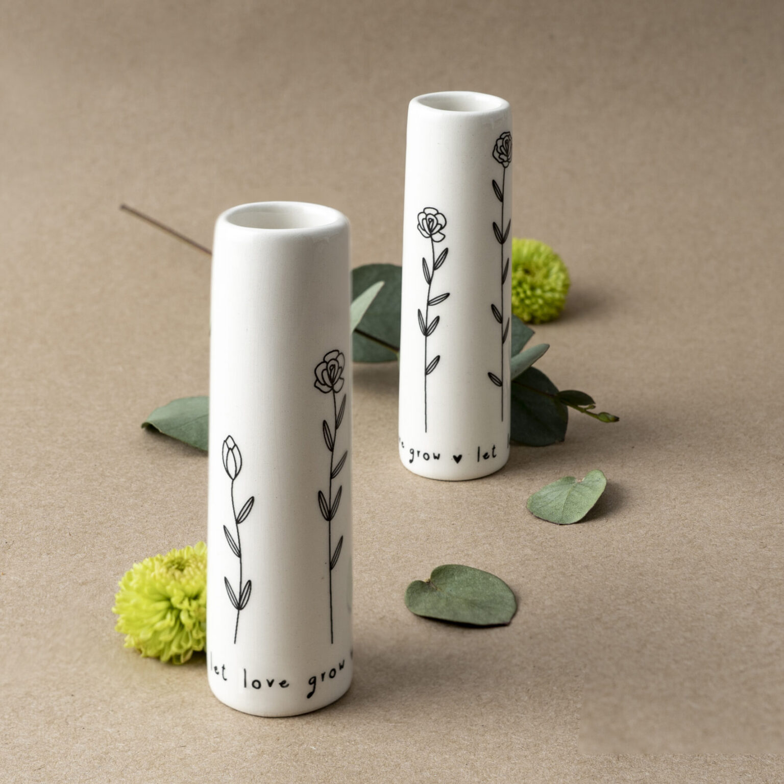 Two mini white vases with delicate floral design in black.