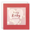 Red card with a window on the front which contains heart shaped paper confetti. A pale coloured hear decorates the front of the card with the text Happy Ruby Anniversary in the centre.