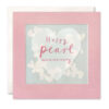 Pink card with a clear window which contains paper confetti hearts. A large heart decorates the front of the card with the text Happy Pearl Anniversary.