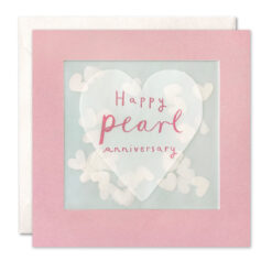 Pink card with a clear window which contains paper confetti hearts. A large heart decorates the front of the card with the text Happy Pearl Anniversary.