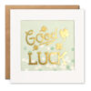 Square card with a clear window on the front which contains green and white paper circle confetti. On the front of the window the gold text reads Good Luck and is surrounded by gold four leaf clovers.