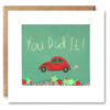 Square card featuring an illustration of a red car and the text 'You Did it!'. The card features a clear window which contains glitter and sequins.