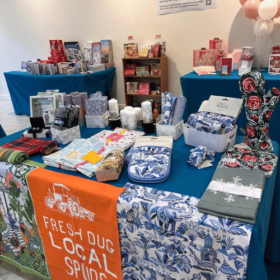 Tea towels, oven gloves, candles and other items on display in a shop.