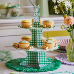 Cupcakes sit on a Green and white gingham afternoon tea stand with a rabbit on the top.