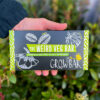 A hand holds a rectangular growbar which has the text 'The Weird Veg Bar. Growbar.'