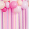 Pink and purple paper streamers hang down with balloons at the top.