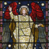 Christmas card with a stained glass image of and angel with red wings holding a crown