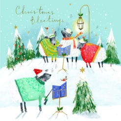 Christmas card with an image of sheep in woolly jumpers singing on a snowy hill in front of christmas trees