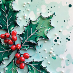 Christmas card with a close up image of holly with red berries laid on snow