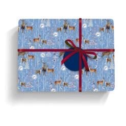 Gift wrapped in this blue paper with deer and snowy trees, tied with red and navy ribbon and finished with a round navy tag.