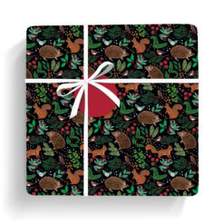 Gift wrapped in this black paper featuring woodland animals, festive leaves, and berries; tied with white ribbon and red gift tag.