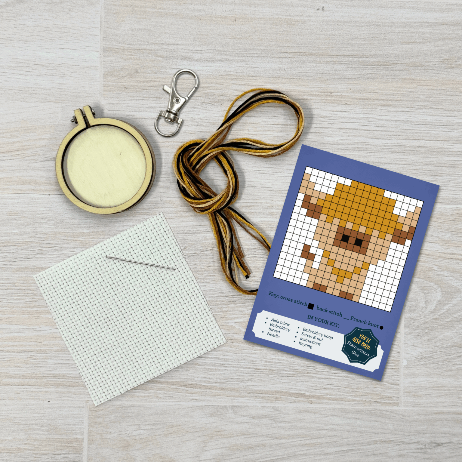 Contents of this product including embroidery hoop, keyring, fabric, needle, thread, and Highland Cow pattern