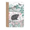 Front cover of this notebook featuring a countryside illustration including a hedgehog among wildflowers, with a bird on a branch above rolling fields and distant trees.