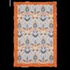 Tea towel with bright orange border and block pattern of birds, butterflies, leaves and flowers in orange, blue and white.