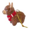 A ceramic highland cow wearing a red and white striped scarf. There is a gold hanging loop.