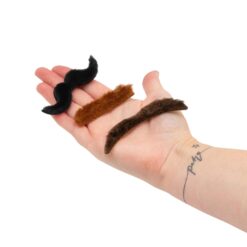 A hand holds three different styles of stick on moustache.
