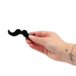 A hand holds a black curly stick on moustache.