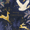 Christmas card with a dark blue background featuring gold and white woodland creatures including a reindeer, owl, and hare, surrounded by stars, moon, and decorative foliage. Elegant gold text reading 'merry CHRISTMAS' appears in the centre.