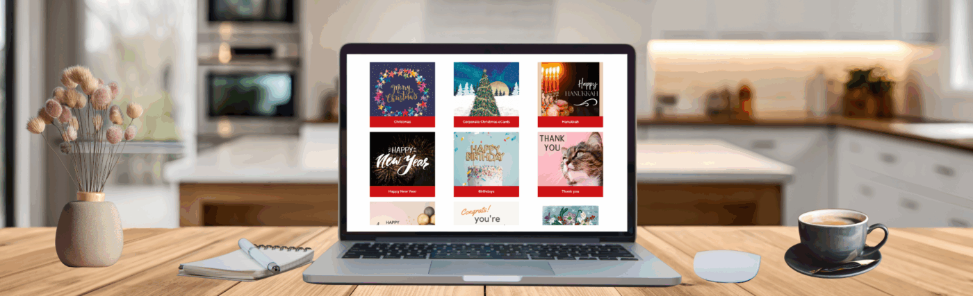 Laptop on a table next to a notepad, vase of flowers, coffee mug and a computer mouse. On the laptop screen are different blocks featuring ecards for various occasions.