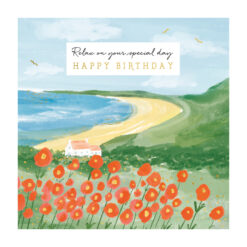 A birthday card featuring a watercolour illustration of a coastal view along a long beach. Before the beach is a white house and a field of red poppies. Text in a white box reads 'Relax on your special day. Happy Birthday'.
