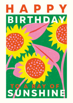 Birthday card featuring a bright, colourful illustration of sunflowers against a green background. Large text reads 'Happy Birthday to a Ray of Sunshine'.