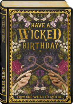 Card in a book design with an illustration of two hands holding sticks which come together in the centre with a mystical trail of purple. The hands are surrounded by florals and botanicals and there is a gold foil border against a dark background. Text in gold reads 'Have a wicked birthday. From one witch to another'.