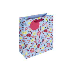 A light blue gift bag decorated with colourful flowers and finished with a pink ribbon handle and round tag.