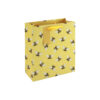 A yellow gift bag with an all‑over bee pattern, finished with yellow ribbon handles and a matching tag.