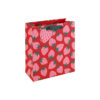 A medium gift bag with a bright red background, covered in pink strawberries with green leaves and finished with green ribbon handles.