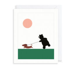 A black bear is being pulled along the green grass by a brown sausage dog on a lead. There is a circular orange sun above them.