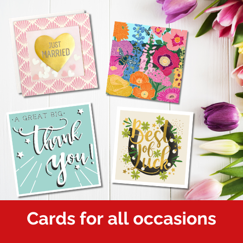 four cards lie on a white wooden table next to a display of colourful tulips.