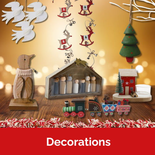 A selection of Christmas decorations on a wooden table against a glowing backdrop illuminated with fairy lights. Decorations include wooden penguin, nativity scene, mini train, house tea light holder, tinsel and garlands.